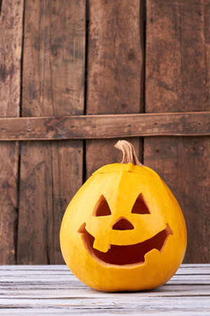 Funny Halloween pumpkin on wood background. Halloween holiday jack lantern. Handmade decoration for seasonal holiday. How to carve Halloween pumpkins.の写真素材