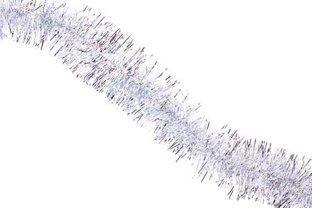 Silver tinsel on white background. Silver shiny Christmas garland isolated on white background, diagonal position. Beautiful decoration on Christmas holiday.の写真素材