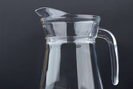 Clear glass jug on black background. Blank glass pitcher on dark background, cropped image. Glass container for water.の写真素材
