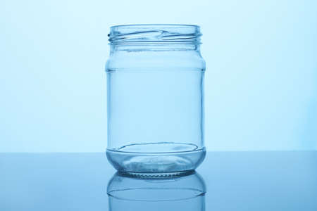 Empty glass jar. Reflective surface, blue lighting.の写真素材