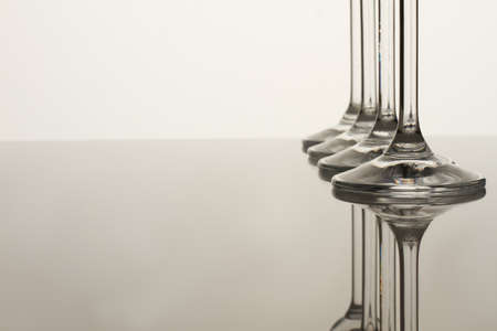 Glass cups stems. Reflective surface. White background and free space for text.の写真素材