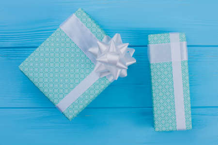Two green boxes wrapped in patterned green paper. Top view. Blue wood background.の写真素材