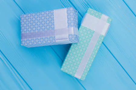 Gift boxes wrapped in patterned paper. Blue wooden background.