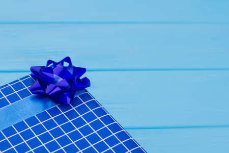 Blue gift box with bow, close up. Blue wood background.の写真素材