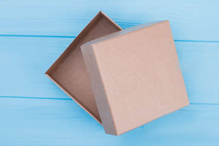 Cardboard craft box, top view. Top view of brown box. Blue wood background.の写真素材