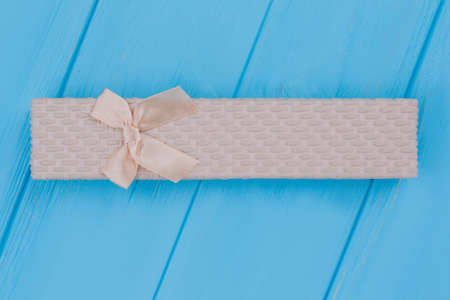 Long present gift box with bow. Top view. Blue wooden background.の写真素材