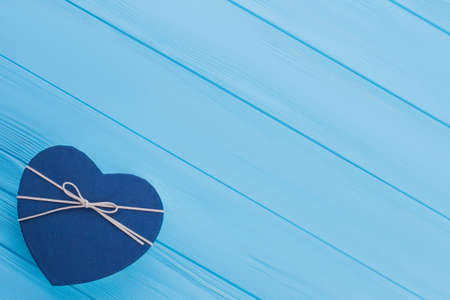 Blue heart shaped gift box with ribbon. Top view. Blue wooden background.の写真素材
