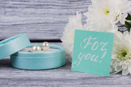 Valentines holiday background with gifts and flowers. Bouquet of white chrysanthemums, box with pearl earrings and card with inscription for you. Holiday greeting card.の写真素材