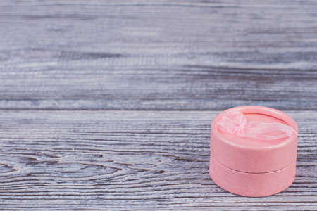 Jewelry gift box and copy space. Pink round jewellery gift box on wooden background with free space for text.の写真素材