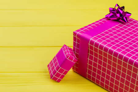 Christmas gifts background. Gift boxes wrapped in beautiful pink paper with bow on yellow background. Christmas greeting card.の写真素材