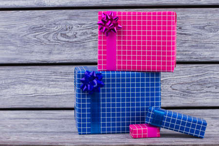 Colorful wrapped gift boxes on wooden background. Beautiful wrapping and bows. Christmas greeting card.の写真素材