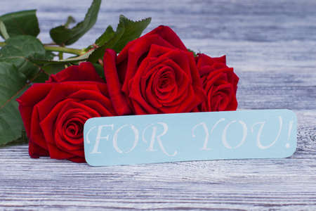 For you card and red roses. Romantic background with red roses and love message on wooden background. Happy Valentines Day.の写真素材