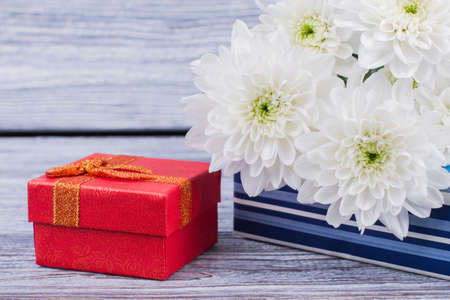 Luxury jewelry gift box and flowers. Red jewelry gift box and white chrysanthemum flowers close up. Valentines Day, love and holidays concept.の写真素材