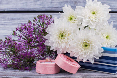 Love design on wooden background. Golden ring in gift box and blooming flowers close up. Valentines Day or 8 march concept.の写真素材