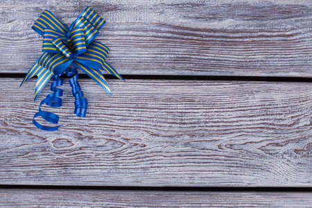Blue gift bow on vintage wooden background. Beautiful Xmas bow with copy space. Element of festive decor.の写真素材
