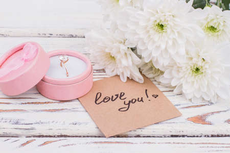 Ring in gift box and a bouquet of chrysanthemums. Beautiful white flowers, engagement ring and love...