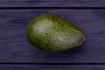 Fresh green avocado on black wooden background.
