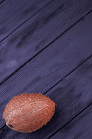 Big brown coconut on dark wooden surface with text space, top view.