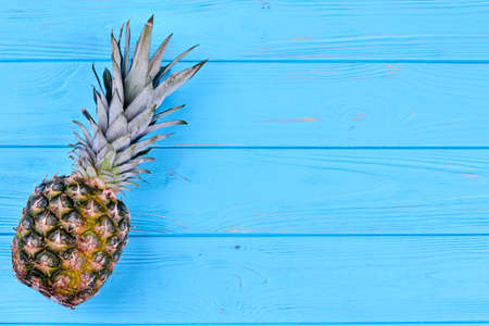 Whole hawaiian pineapple fruit on blue wooden table with text space.の写真素材