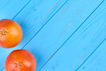 Fresh juicy grapefruits on blue wooden background with text space, horizontal image.