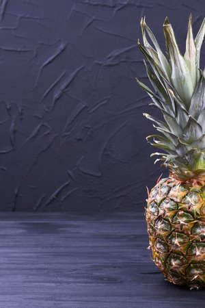 Delicious organic pineapple on black wooden background