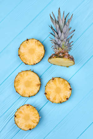 Sliced pineapple on blue wooden background. Flat lay freshly cut pineapple on color wooden surface, top view.の写真素材