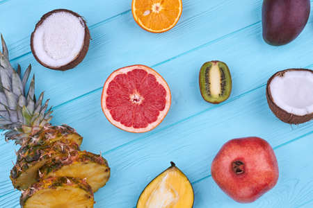 Mix of tasty tropical fruits on wooden background. Flat lay assortment of delicious exotic fruits on colorful wood.の写真素材
