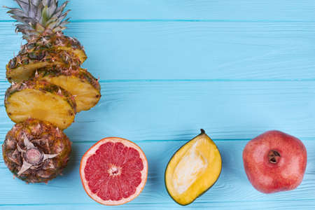 Tropical fruits background with copyspace. Ripe exotic fruits including sliced pineapple, grapefruit, mango and pomegranate on color background with text space.の写真素材