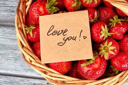 Ripe juicy strawberries in basket and card love you.の写真素材