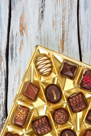 Box filled with chocolate pralines on vintage wooden boardの写真素材