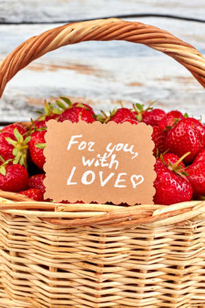 Ripe strawberries in basket and romantic message.の写真素材