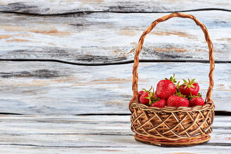 Ripe sweet berries in basket on rustic wooden background and copy space.の写真素材