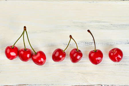 Row of sweet juicy cherries on light wooden surface.の写真素材