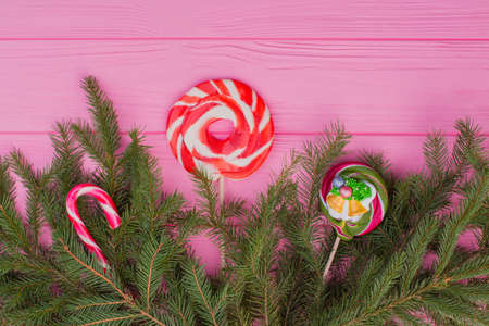 New Year or Christmas background. Christmas background with candies and fir tree border on pink wooden surface. Winter season decor.の写真素材