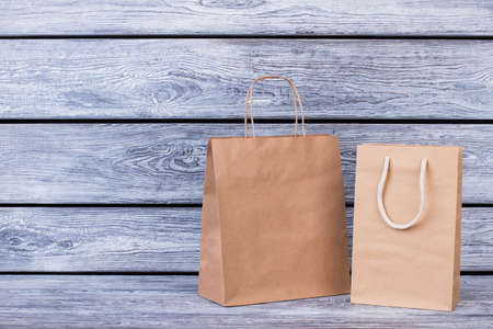 Brown paper shopping bags on wooden background. Recycle paper carrier bag with clipping path, horizontal image.の写真素材