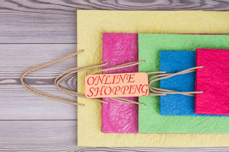 Beautiful shopping bags on wooden background. Colorful paper bags and card with inscription online shopping. Gift bags for shops.の写真素材