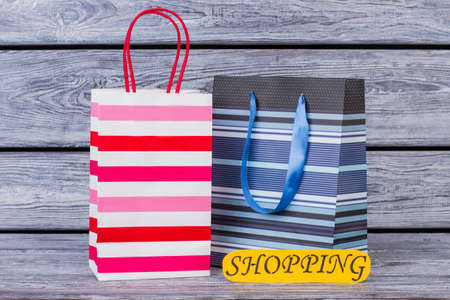 Shopping bags on wooden background. Paper shopping packets and color card with inscription shopping. Holiday sales concept.の写真素材