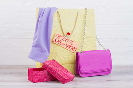 Paper shopping bag with purchases. Female apparel in carrier bag, pink leather handbag, gift box and...
