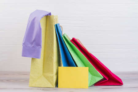 Multicolored paper shopping bags with purchases. Colorful paper carrier bags and blank yellow card.