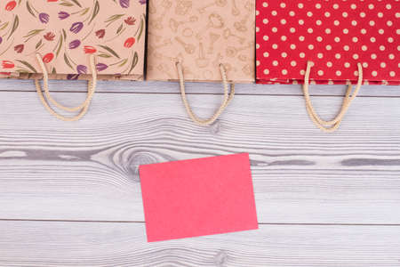 Border from paper shopping bags on wooden background. Set of printed paper bags and blank paper card.の写真素材