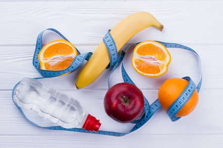Fresh fruits, bottle of water and measuring tape. Vegetarian food and healthy eating concept. The...