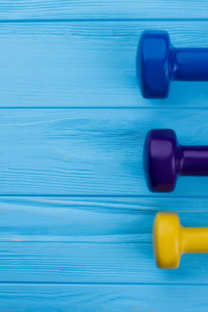 Colorful dumbbells with blank space. Female dumbbell weights, vertical image. Sport and diet...