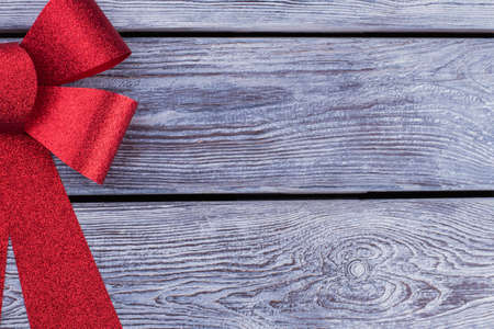 Red festive bow with copy space. Big Christmas bow on wooden background with text space. Rustic...
