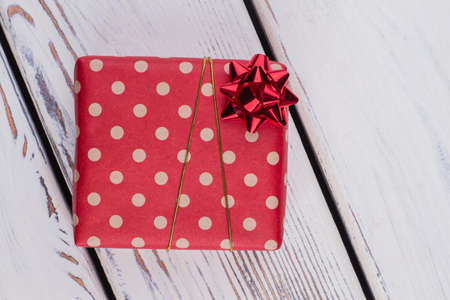 Christmas gift wrapped in red dotted paper. Present box wrapped in patterned paper and tied with golden ribbon. Gift for her.の写真素材