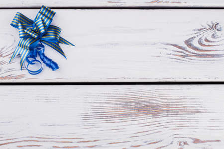 Festive blue gift bow and with space. Blue Christmas bow on light wooden background with free space for text. Xmas greeting card.の写真素材