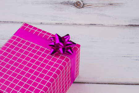 Pink gift box and copy space. Beautiful Christmas present box on white wooden background. Holiday...