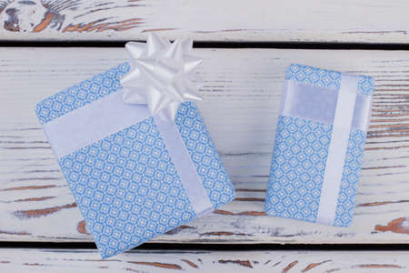 Blue gift boxes on wooden background. Present boxes wrapped in light blue paper with ribbon. Birthday surprise concept.の写真素材