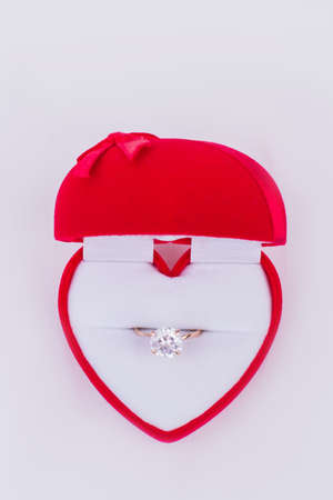 Red gift box with diamond ring. Heart-shaped velvet box with engagement ring. Valentines Day...