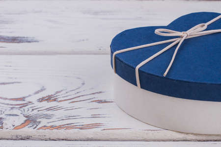 Heart-shaped gift box and copy space. Blue Valentines Day gift box on vintage wood background....