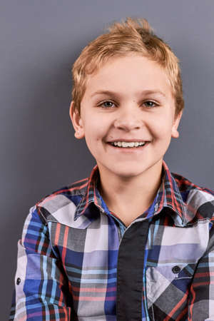 Portrait of happy smiling little boy. Close up studio portrait of cheerful smiling boy on grey...